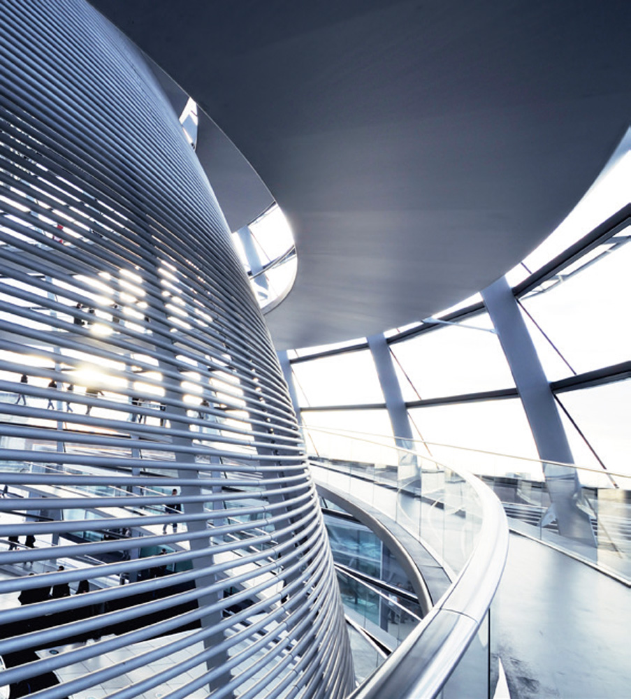 Das Innere der gläsernen Kuppel des Reichstagsgebäudes in Berlin zeigt eine spiralförmige Struktur aus Stahlträgern und horizontalen Lamellen, die das Tageslicht filtern. Besucher sind auf einer gewundenen Rampe zu sehen, die nach oben führt und Ausblicke auf die Stadt ermöglicht. Die moderne Architektur kontrastiert mit dem historischen Gebäude. Das Innere der gläsernen Kuppel des Reichstagsgebäudes in Berlin zeigt eine spiralförmige Struktur aus Stahlträgern und horizontalen Lamellen, die das Tageslicht filtern. Besucher sind auf einer gewundenen Rampe zu sehen, die nach oben führt und Ausblicke auf die Stadt ermöglicht. Die moderne Architektur kontrastiert mit dem historischen Gebäude.